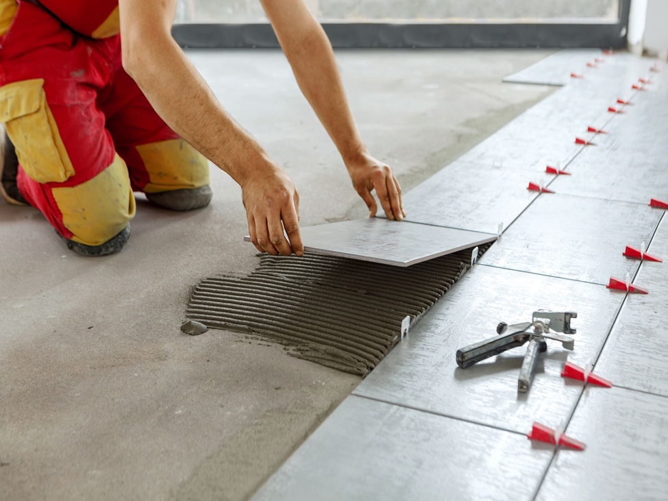 工人将瓷砖粘在混凝土地板上。使用我们的高品质添加剂Bermocoll, Dissolvine和Expancel，确保一致性和提高您的建筑干粉材料的质量。