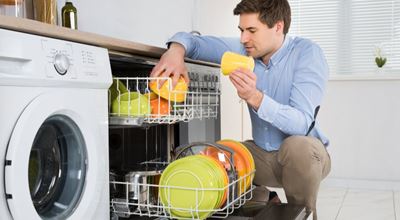 安排在洗碗机的年轻愉快的人盘在现代厨房里。Nouryon的技术 - 表面活性剂，螯合剂，生物聚合物，聚合物 - 提供了增强自动洗碗机洗涤剂的功能。