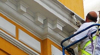 A man in a sky lift painting masonry on a building using silicate paint. Levasil colloidal silica and Bermocell CMC are added to silicate paint to improve paint stability, adhesion, durability and weather resistance. 
